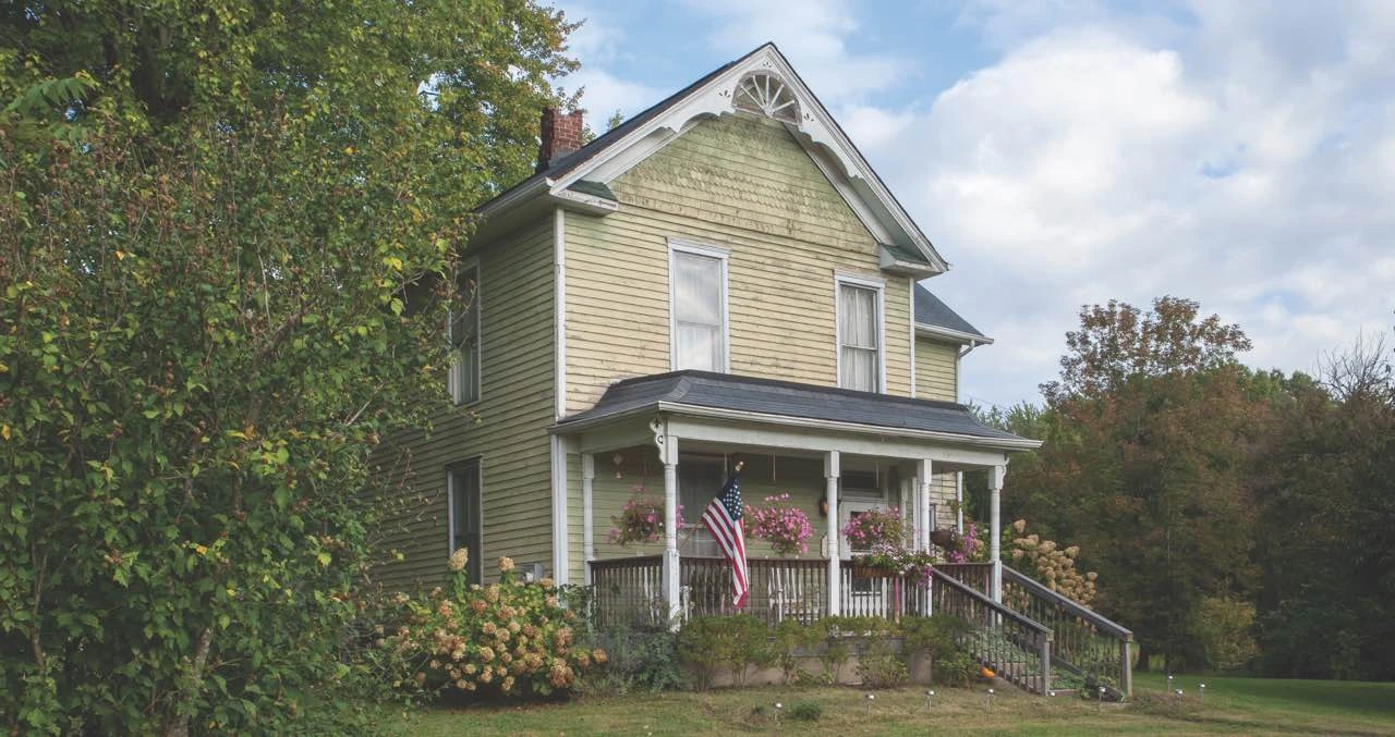 Before: two-story house with faded yellow siding