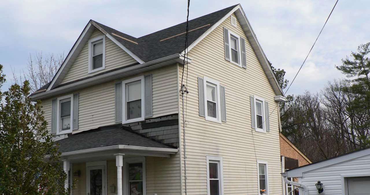 Before: two-story house with damaged yellow siding