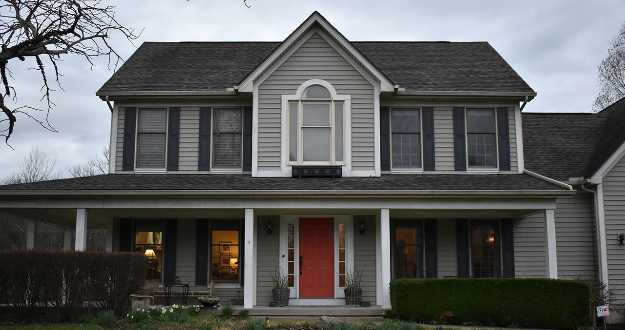 Before: two-story house with old siding and window shutters